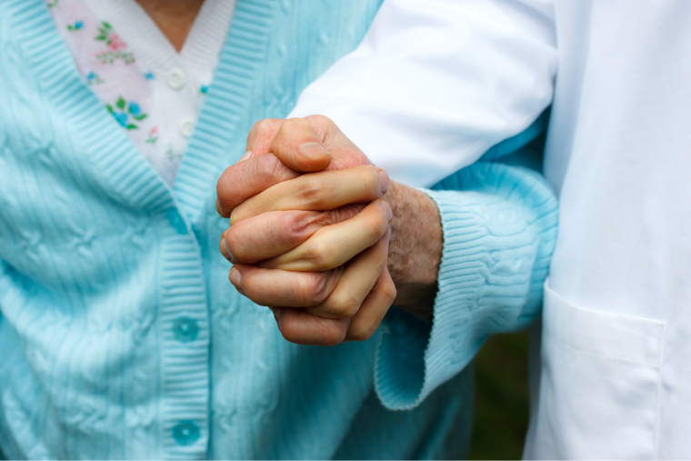 medical provider holding an elderly woman's hand
