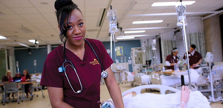 BSN student in maroon scrubs in simulation classroom