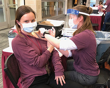 Anya giving a COVID-19 vaccine to Emma Butzer