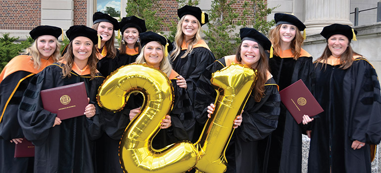 2021 school of nursing graduates holding a "21" gold balloons