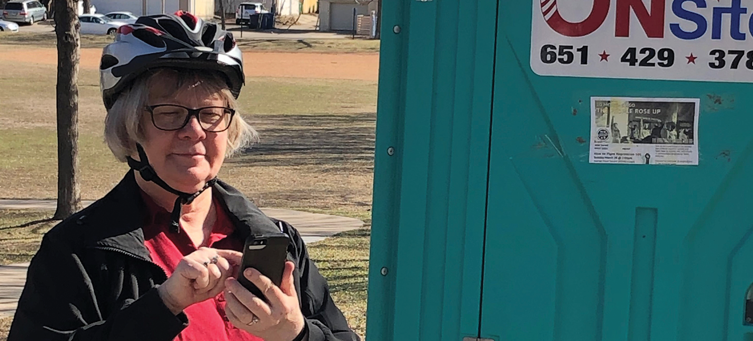 Donna Bliss next to a portable toilet