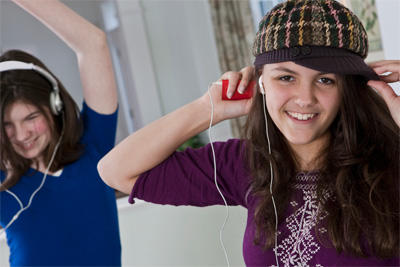 two adolescent females listening to music with headphones