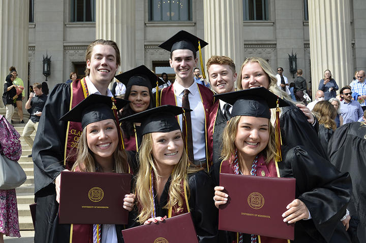 eight school of nursing graduates with three holding their diplomas
